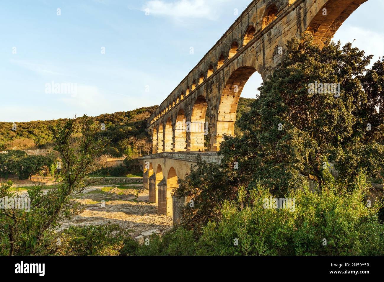Tre livelli dell'antico acquedotto romano Pont Du Gard che si riflette nel fiume Gardon, nel sud della Francia Foto Stock