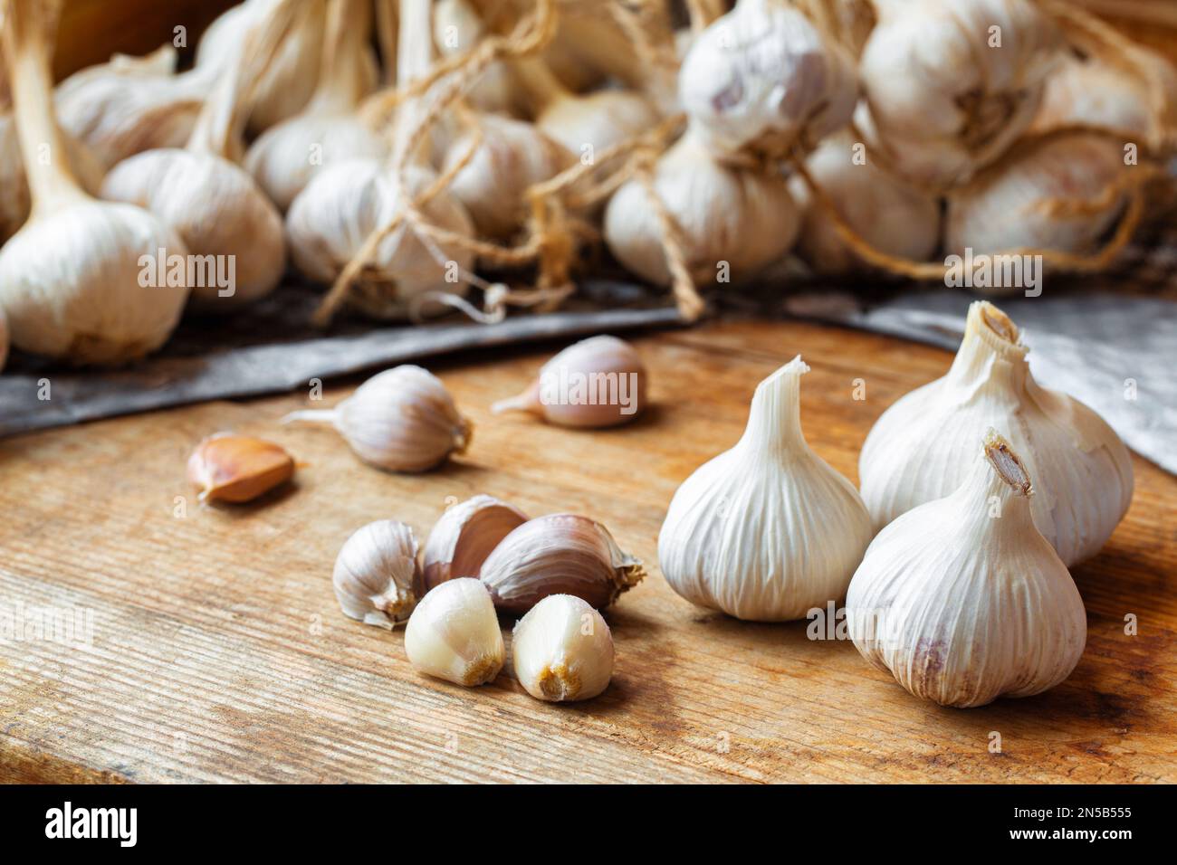 Bulbo d'aglio prodotto in casa su un tavolo rustico in legno. Spicchi d'aglio appena sbucciati. Foto Stock