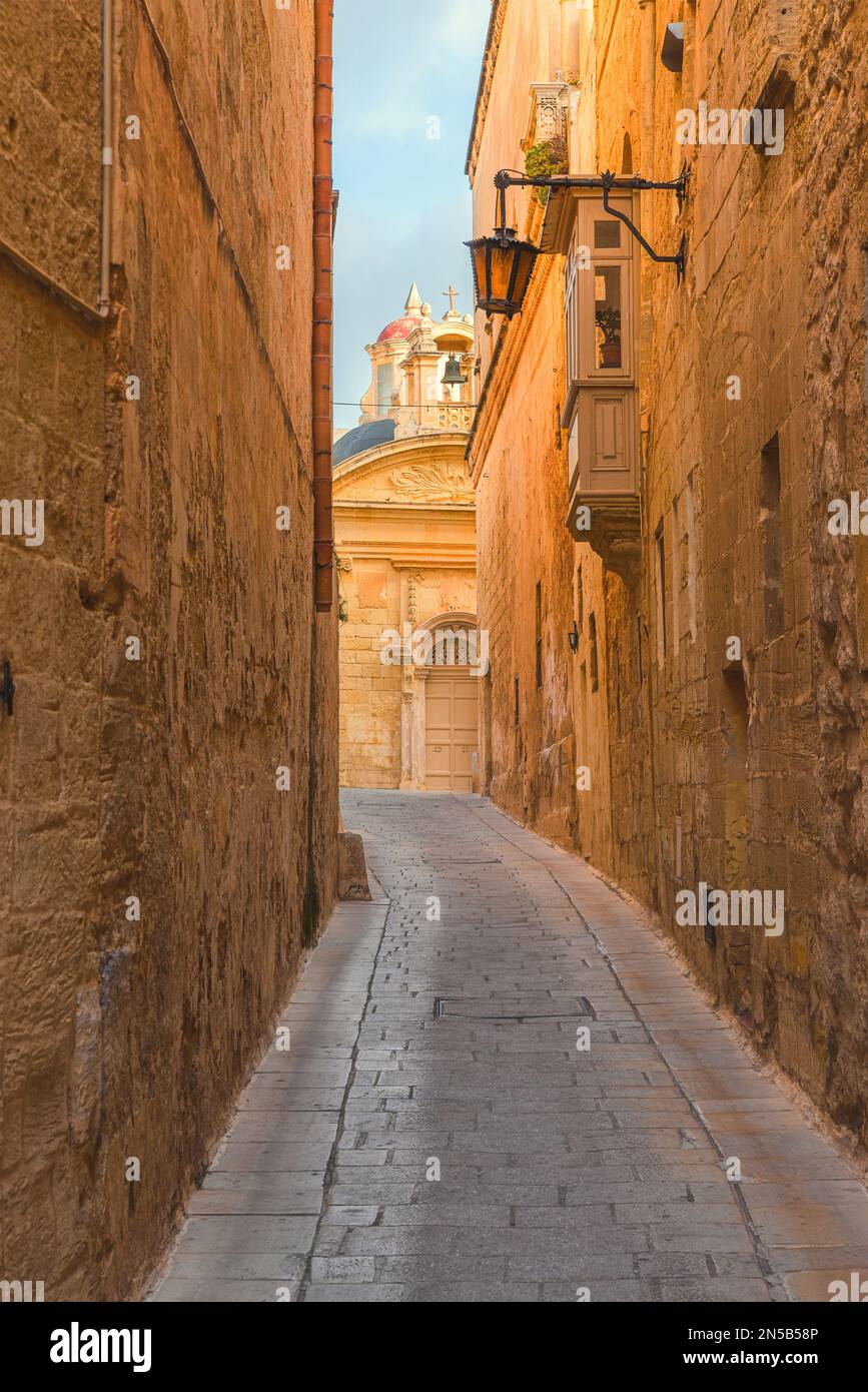 Vecchia strada vuota medievale con luci di strada nella città di Mdina, Malta. Orientamento verticale. Destinazione di viaggio in Europa. Orientamento verticale Foto Stock