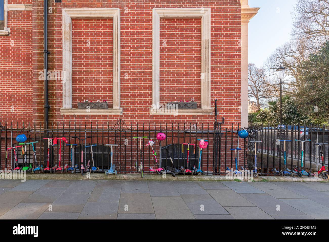 I bambini Scooters si sono allineati contro le ringhiere fuori dalla Knightsbridge School, Lennox Gardens, Londra, SW1. Foto Stock