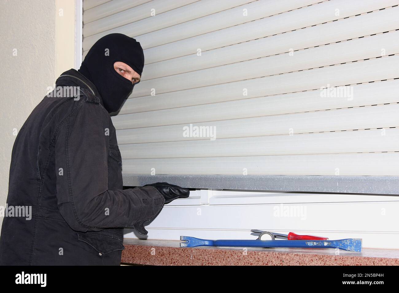 scasso con cacciavite, crowbar e lampada tascabile su una tenda a rullo Foto Stock
