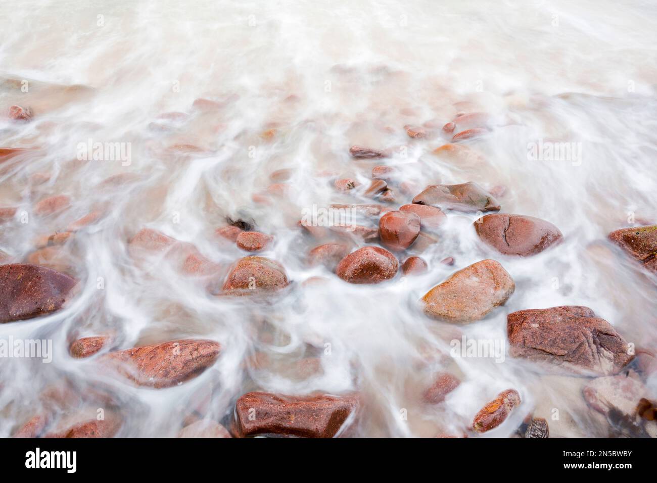 Onde su una spiaggia di pietra rossa sulla costa nord-occidentale della Scozia, Regno Unito, Scozia Foto Stock