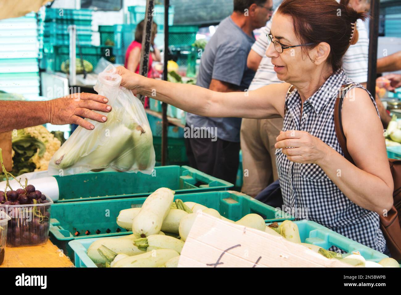 Una donna caucasica bianca di mezza età in un mercato alimentare all'aperto che acquista una borsa di verdure Foto Stock