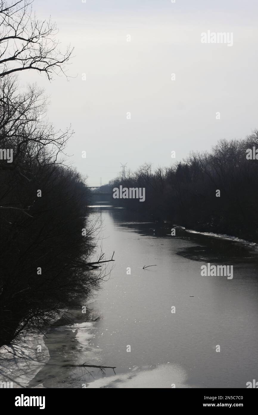 Fiume ghiacciato che si snoda attraverso la foresta selvaggia una giornata invernale fredda e gelida. Foto Stock