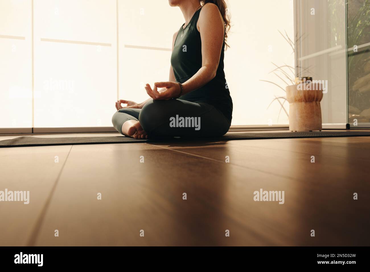 Donna matura meditando mentre pratica hatha yoga. Donna irriconoscibile che fa un esercizio di respirazione mentre si siede in posa facile. Donna anziana segue Foto Stock