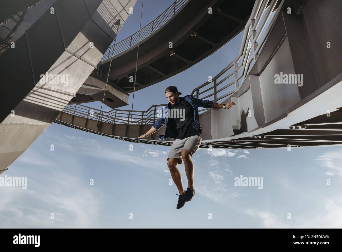 Enorme e rischioso salto da un ponte eseguito da atleta parkour. Libertà in Freerunning Foto Stock