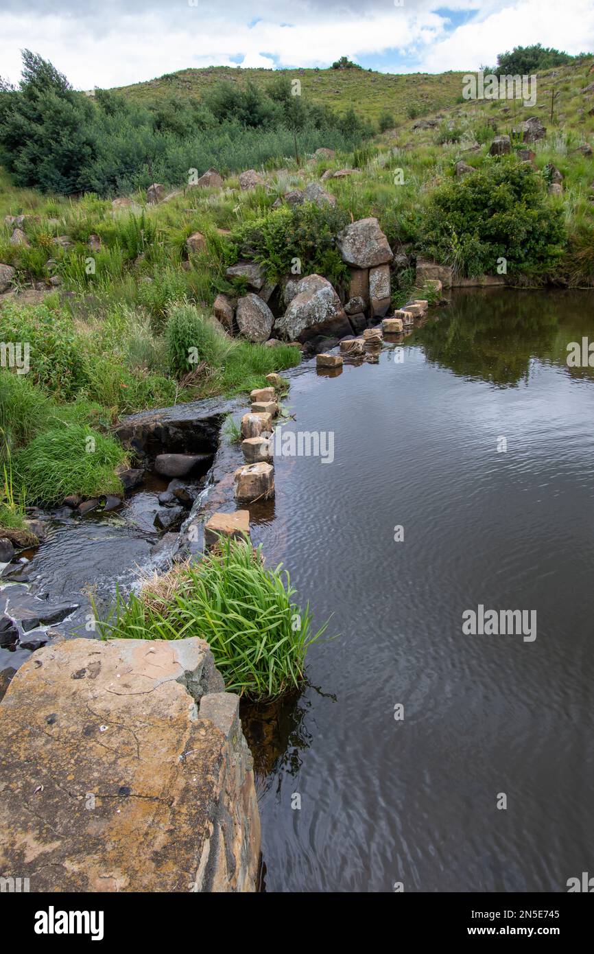 L'acqua gocciola sopra il muro di uno stramazzo in un ruscello di paese Foto Stock