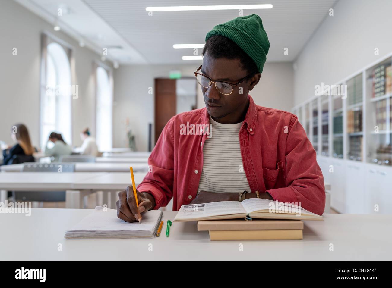 Giovane scienziato afro-americano di talento che indossa gli occhiali che studiano in biblioteca. Concetto di istruzione Foto Stock
