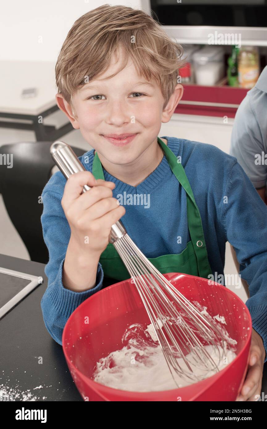 Ragazzo montare la panna con la frusta a filo in classe economica casa, Baviera, Germania Foto Stock