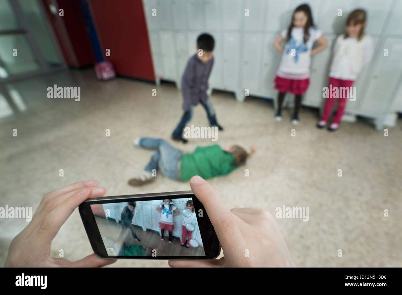 La mano della persona filma due scolari che combattono nel corridoio scolastico con il telefono cellulare, Baviera, Germania Foto Stock