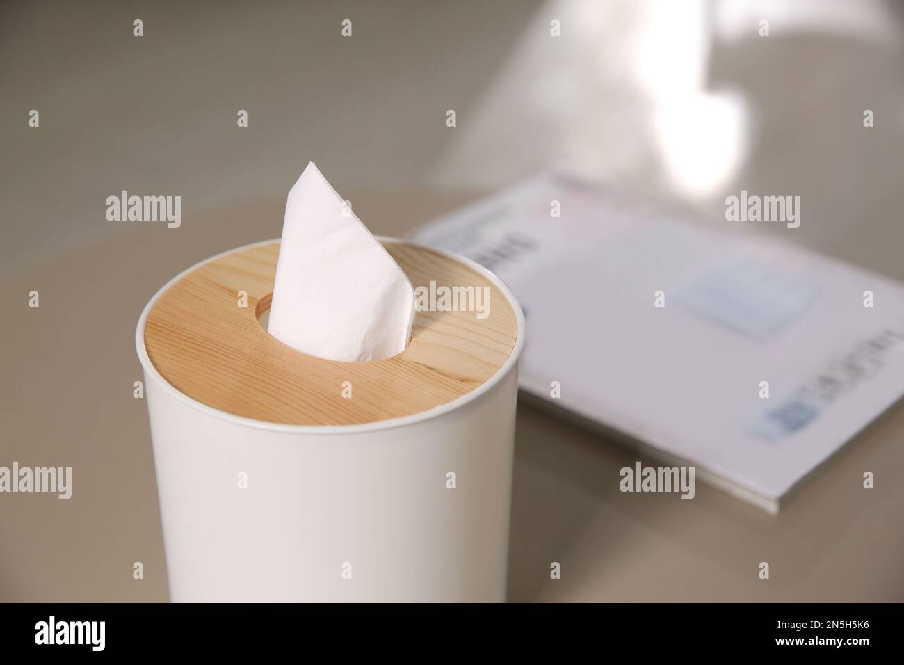 Scatola con fazzolettini di carta su tavolo leggero, primo piano Foto Stock