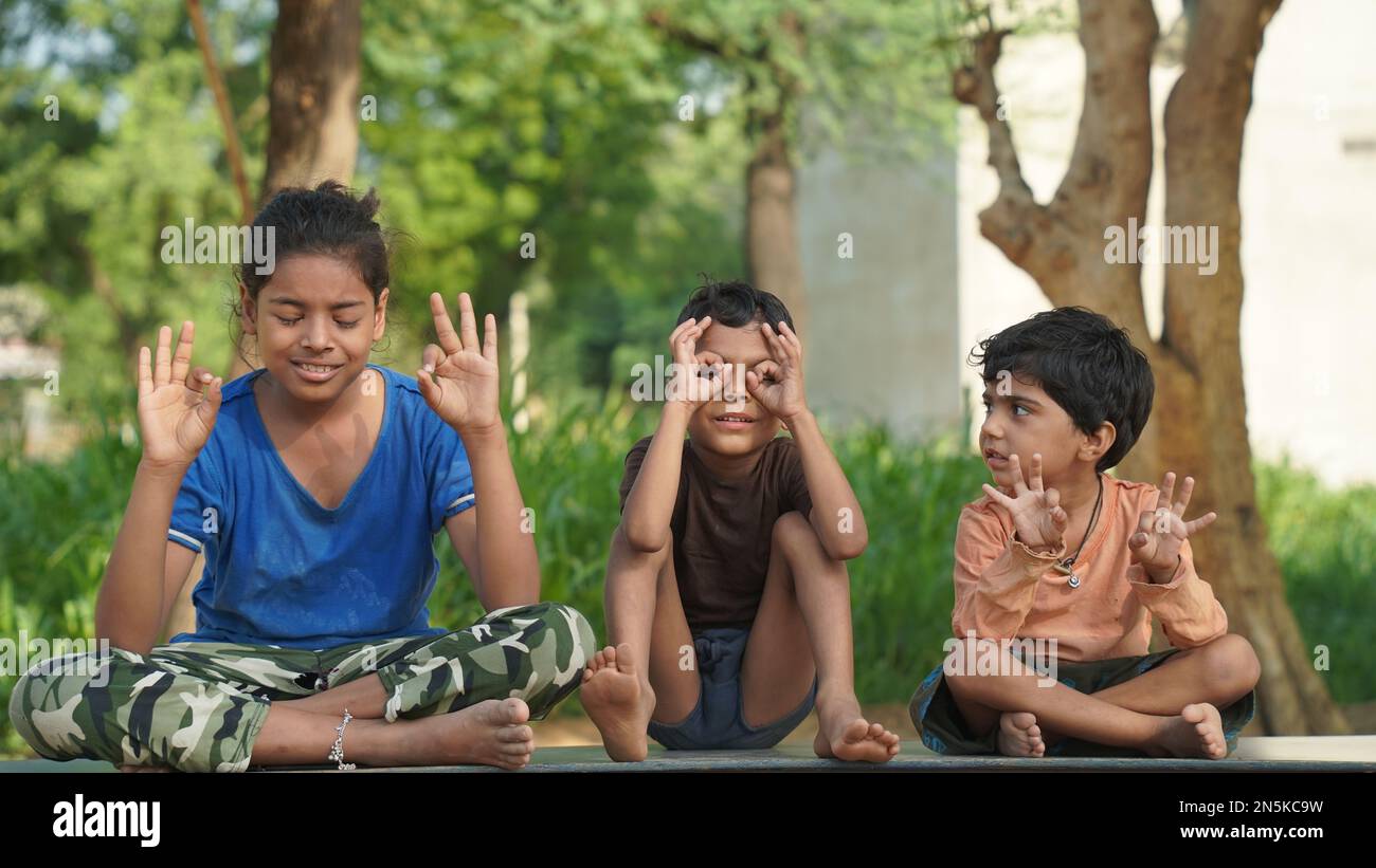 Due bambina indiana e un ragazzo che medita yoga asana su tappetino con gli occhi chiusi nel parco. Foto Stock