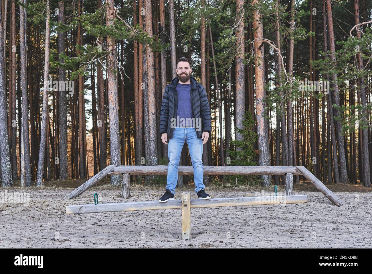 Adulto uomo bearded hipster che rimane in altalena in un'area gioco nella foresta. Concetto di sanita', armonia ed equilibrio. Foto Stock