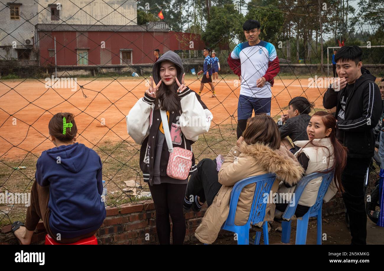 Una giovane ragazza si pone davanti ai suoi amici che sono venuti a guardare una partita di calcio locale a tra Co, vicino Mong Cai a Quang Ninh, Vietnam Foto Stock
