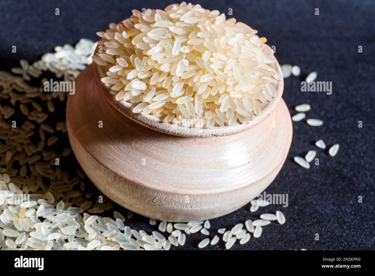 Riso bianco in una ciotola di legno isolata su fondo nero. Il riso è cibo comune della gente asiatica. Foto Stock