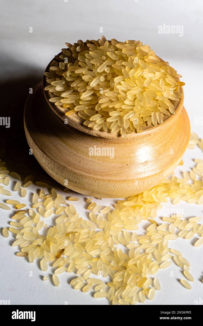 Ritratto di riso dorato in una ciotola di legno isolata su uno sfondo bianco. Il riso è cibo comune dell'Asia Foto Stock