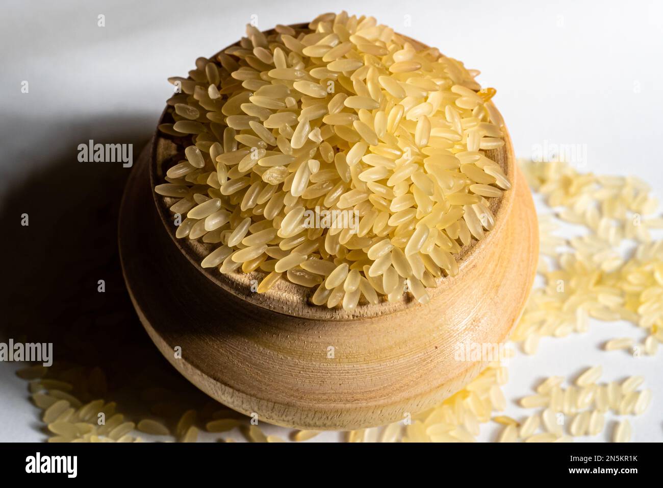 Riso dorato in una ciotola di legno isolata su fondo bianco. Il riso è un alimento comune della gente asiatica. Foto Stock
