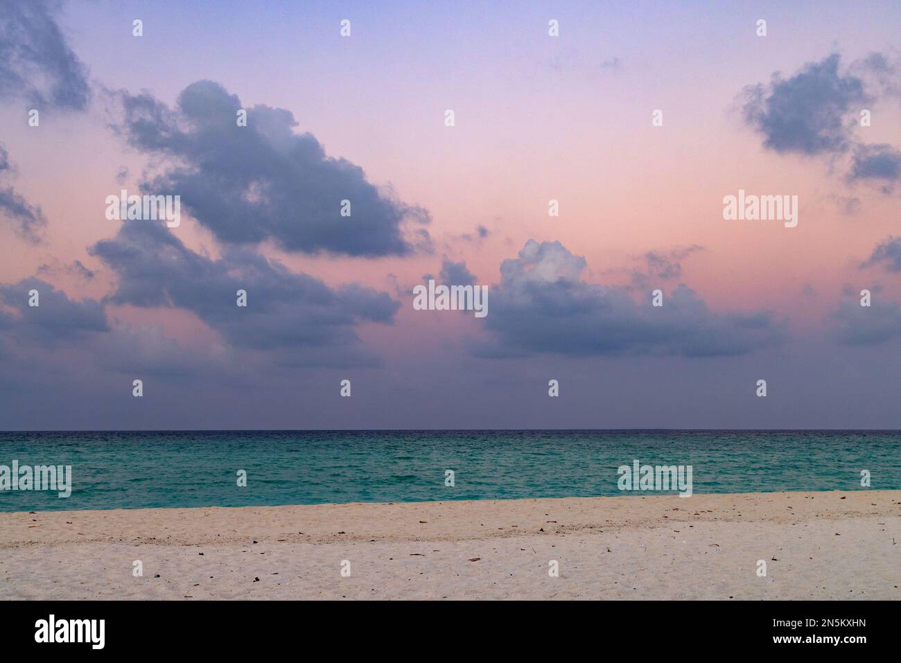 Mare e cielo di sabbia colorati; paesaggio della spiaggia dell'Oceano Indiano subito dopo il tramonto, le Maldive, Asia. Utile per uno sfondo Foto Stock