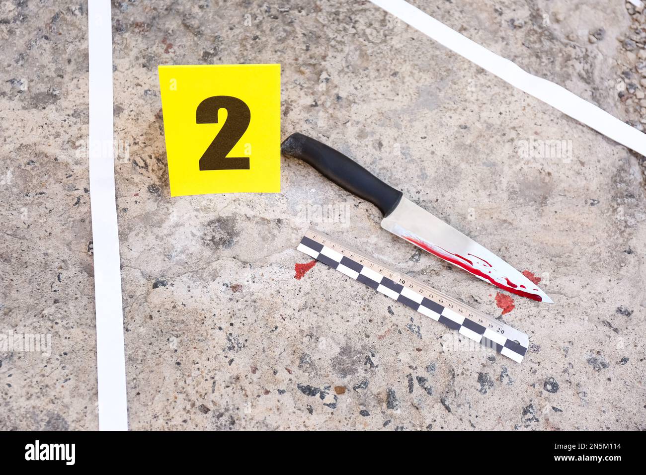 Scena del crimine con coltello sanguinoso e segno di prova sul pavimento, vista dall'alto. Indagine investigativa Foto Stock