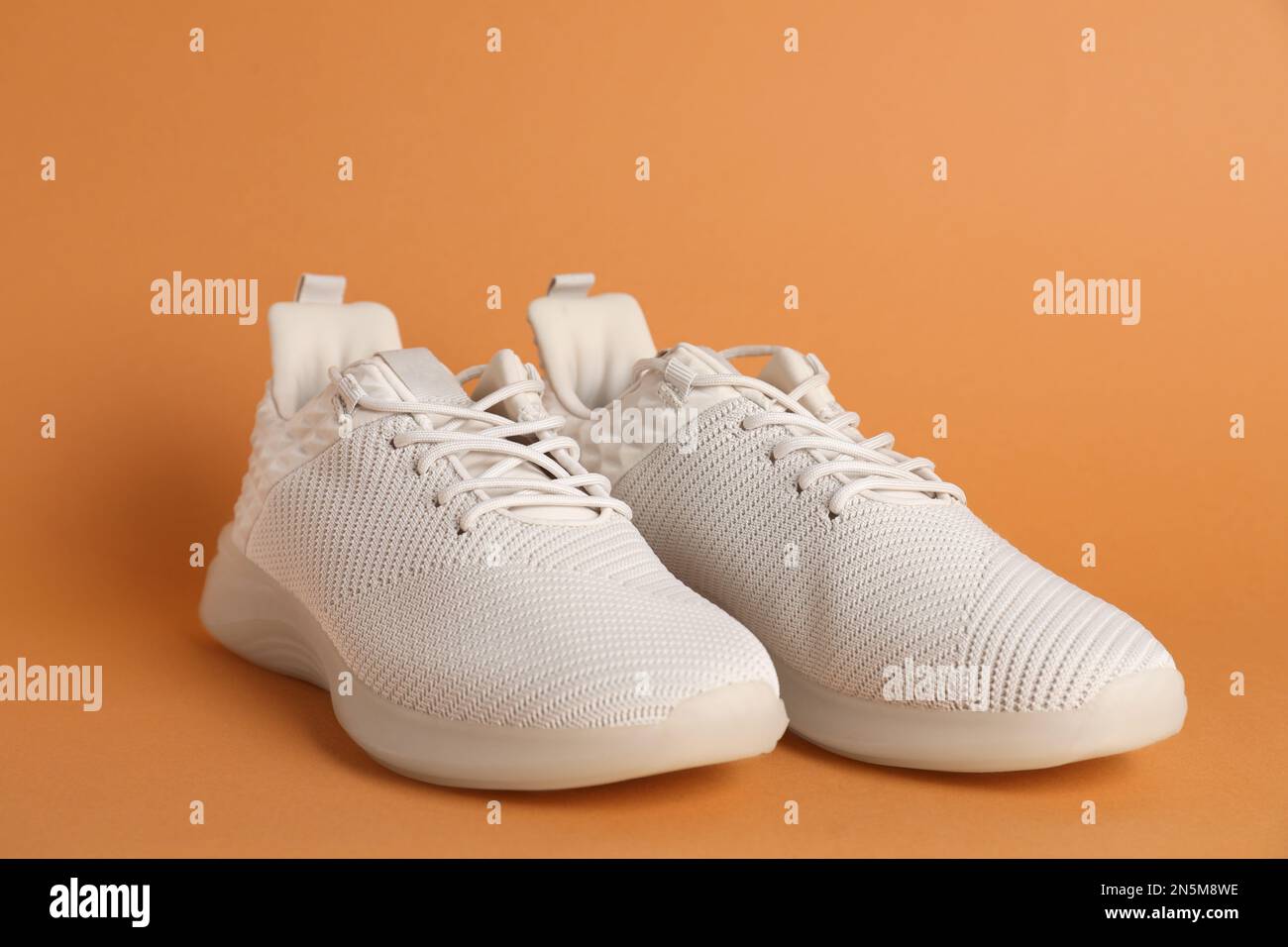 Paio di eleganti scarpe sportive su sfondo arancione, primo piano Foto Stock