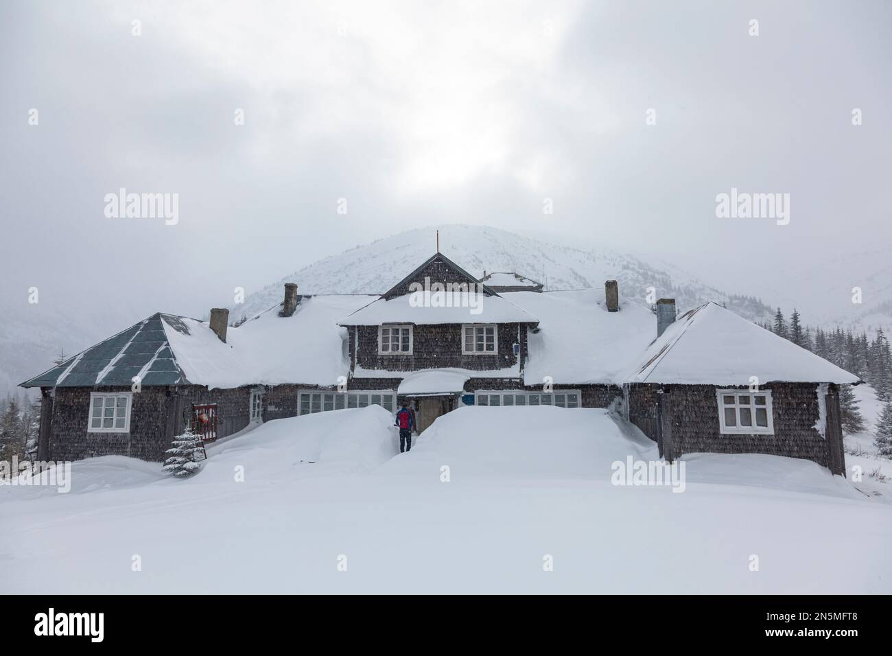 Una vecchia casa turistica coperta di neve sotto una montagna nei Carpazi, Chornohora Foto Stock