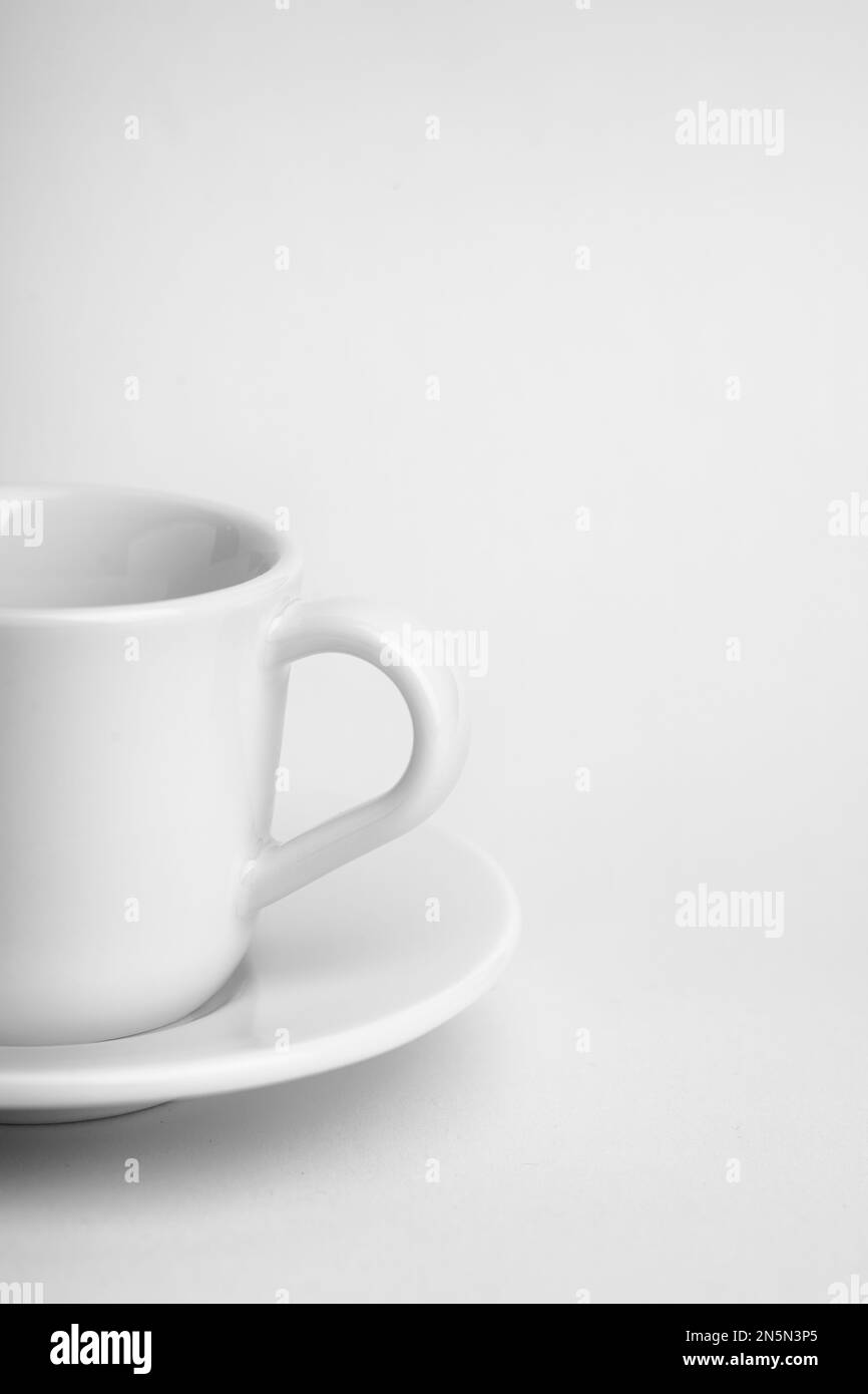 Un colpo verticale di una piccola tazza bianca e un piattino isolato su uno sfondo bianco Foto Stock