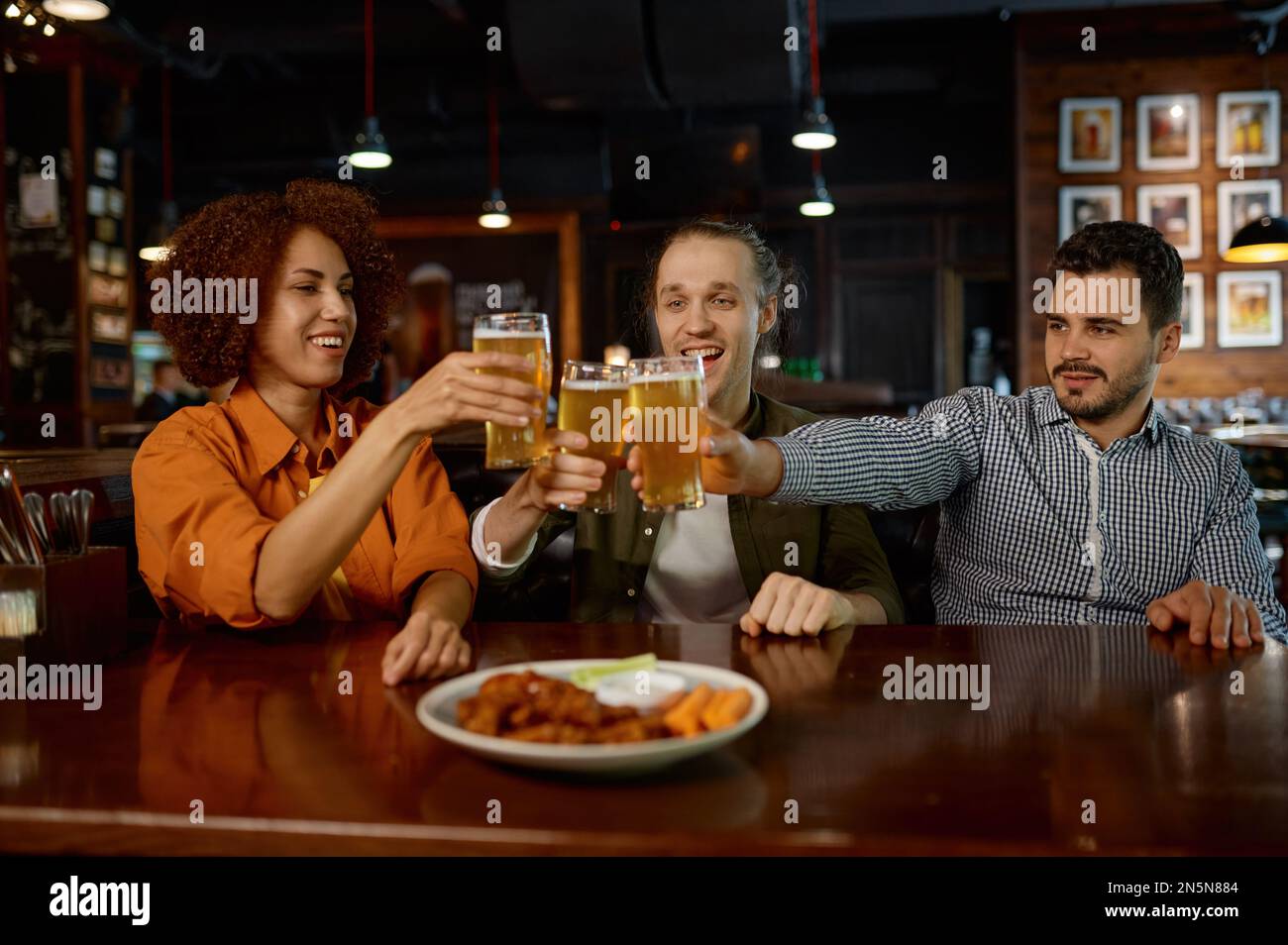 Allegri vecchi amici che si divertono e bevono birra alla spina nel bar dello sport Foto Stock