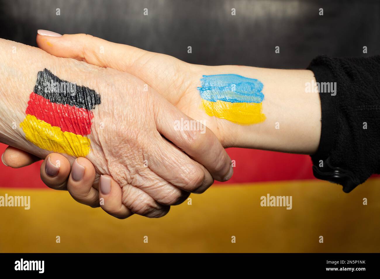 Due mani una con una bandiera disegnata della Germania e la seconda con una bandiera disegnata dell'Ucraina stretta di mano, Unione e unità Foto Stock