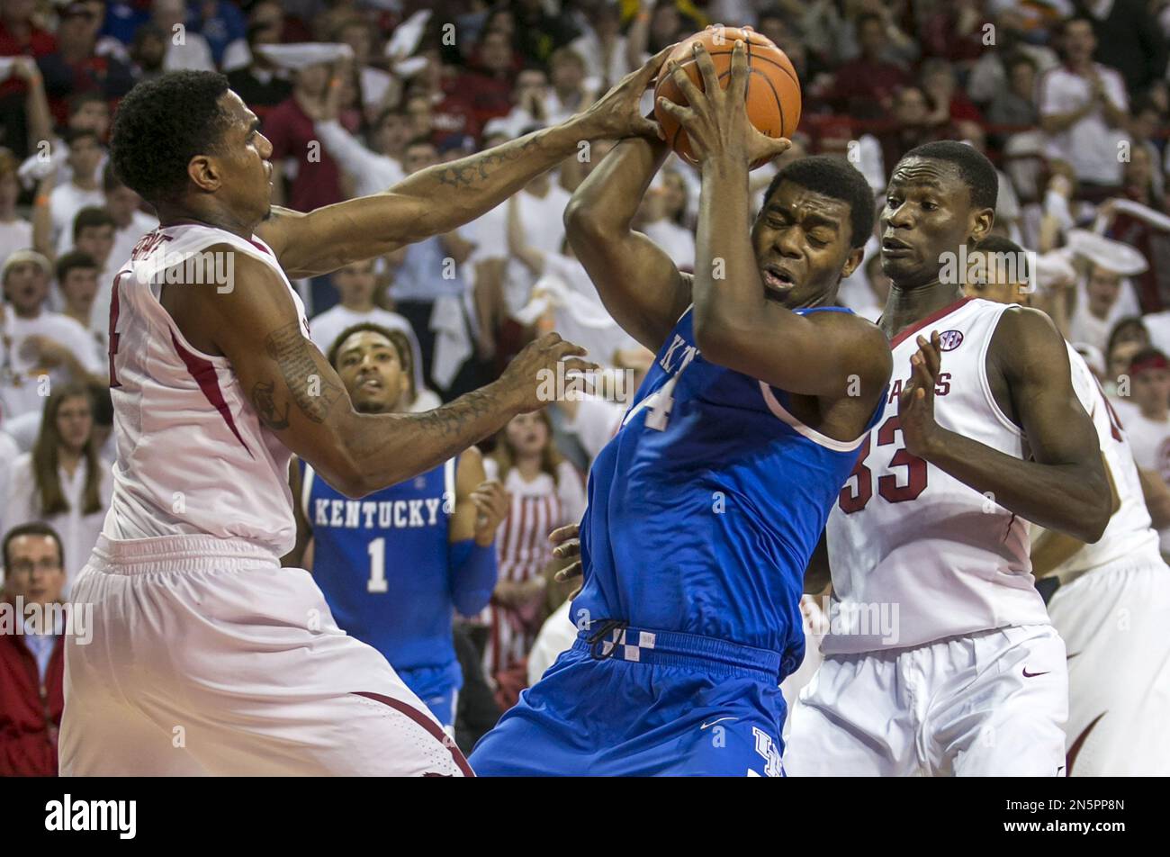 Kentucky center Dakari Johnson, center, is hit under the basket by