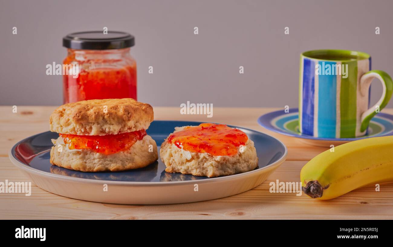 Focaccine fresche con burro e marmellata su di loro con una tazza di caffè e una banana. Foto Stock