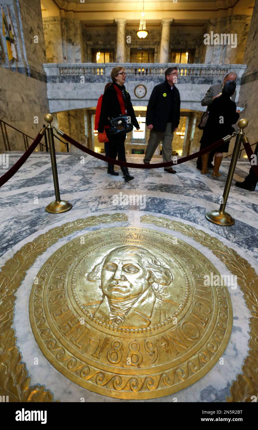 People walk past the state seal of Washington on the floor of the Capitol rotunda on the first day of the 2014 session of the Washington state Legislature, Monday, Jan. 13, 2014, at the Capitol in Olympia, Wash. (AP Photo/Ted S. Warren) Foto Stock