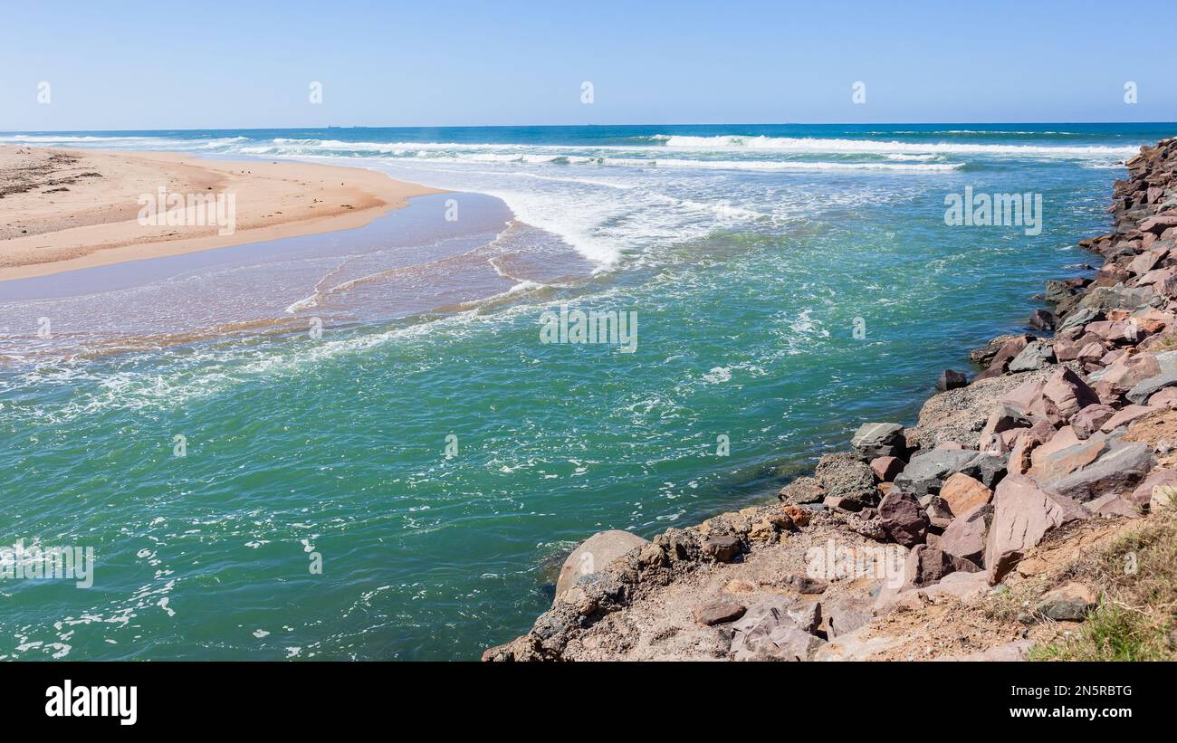 Fiume estuario bocca acqua che sfocia nel mare blu oceano lungo la costa della spiaggia in un giorno d'estate. Foto Stock