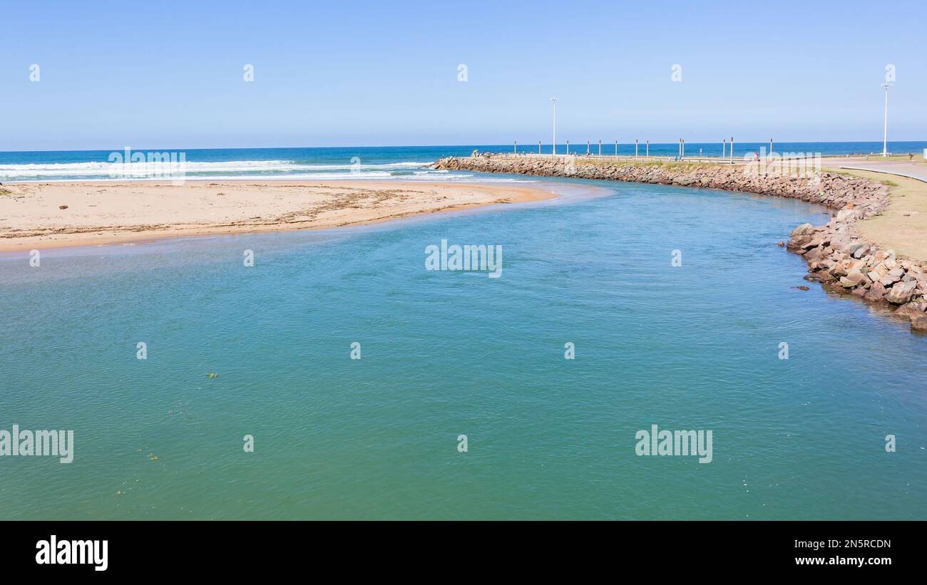 Fiume estuario bocca acqua che sfocia nel mare blu oceano lungo la costa della spiaggia in un giorno d'estate. Foto Stock