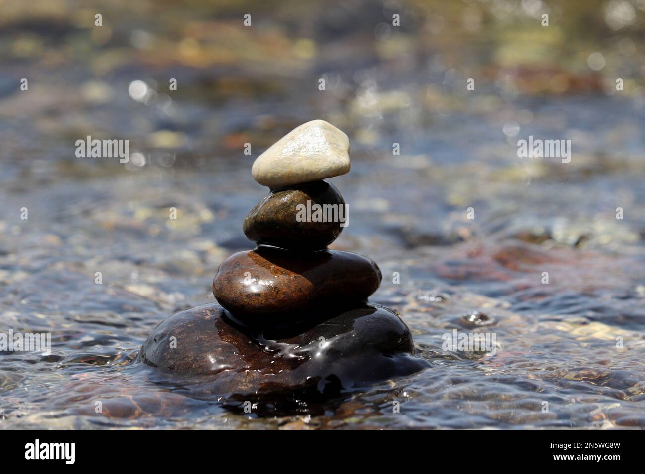 Torre di pietre di ciottoli su sfondo sfocato delle onde del mare. Vacanza in spiaggia, equilibrio e relax concetto Foto Stock