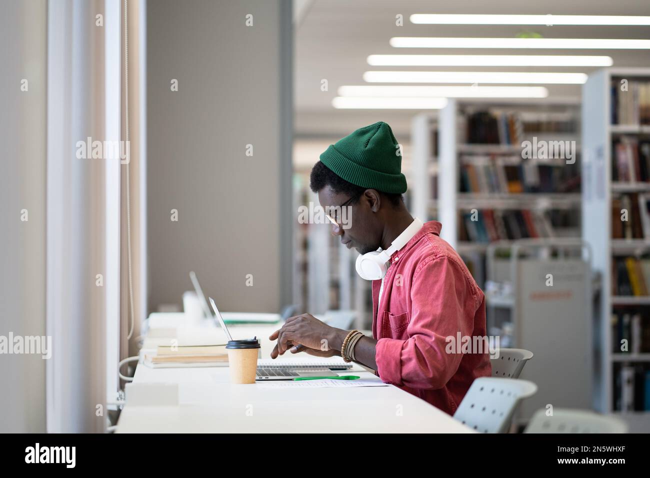 Serio studente uomo prepararsi per l'esame utilizzare il computer portatile per l'istruzione remota presso la biblioteca universitaria Foto Stock