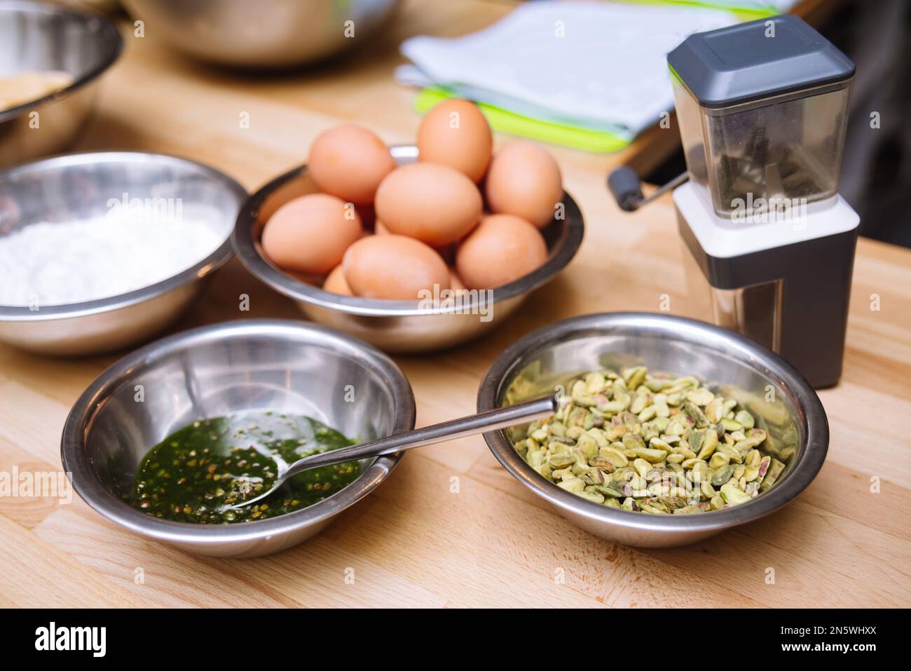 Ingredienti di cibi crudi sul tavolo da cucina prima di cucinare. Uova crude, ciotola di pistacchi, macinacaffè. Foto Stock