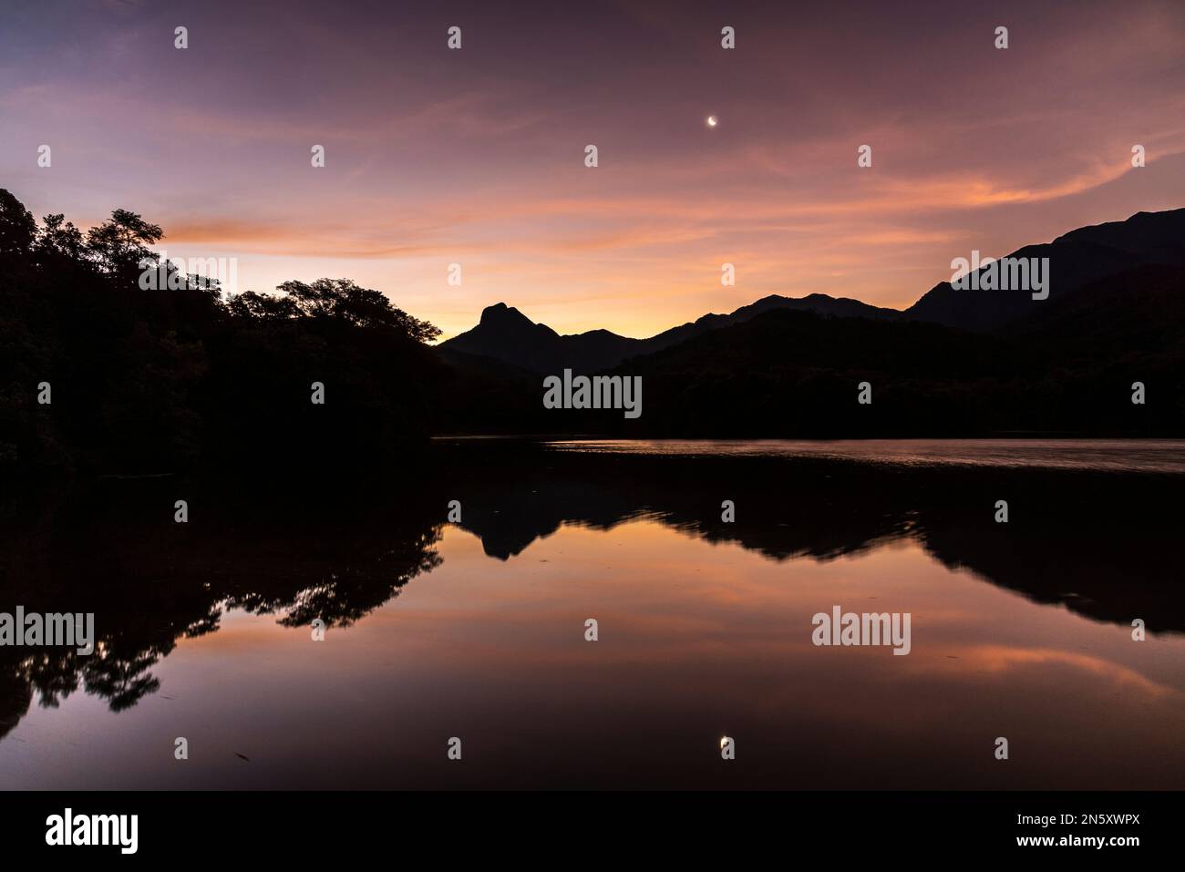 Bellissimo tramonto con nuvole arancioni sul lago della foresta pluviale Foto Stock