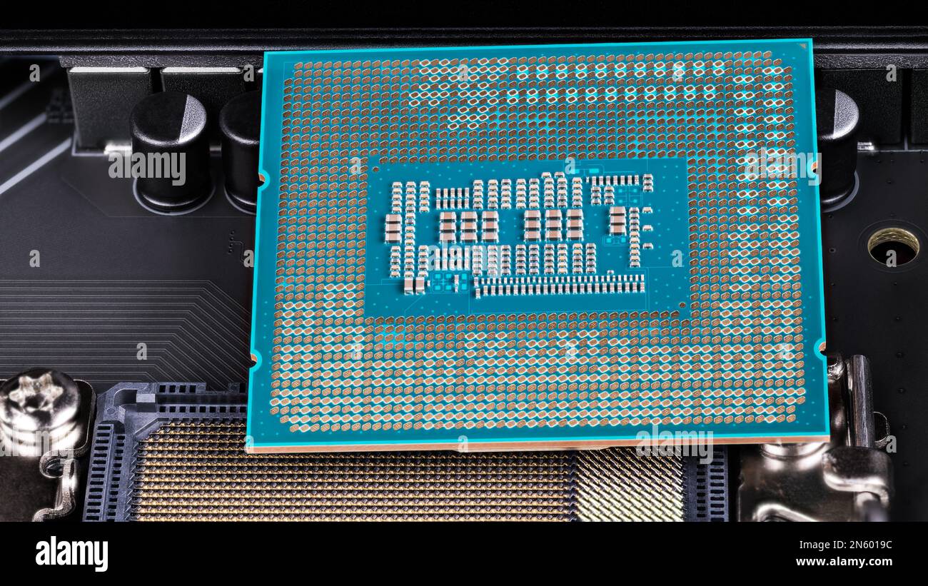 Primo piano tra l'installazione del processore e il socket della scheda madre del computer. Scheda a circuito stampato verde con montaggio superficiale di piccoli componenti elettronici. Foto Stock