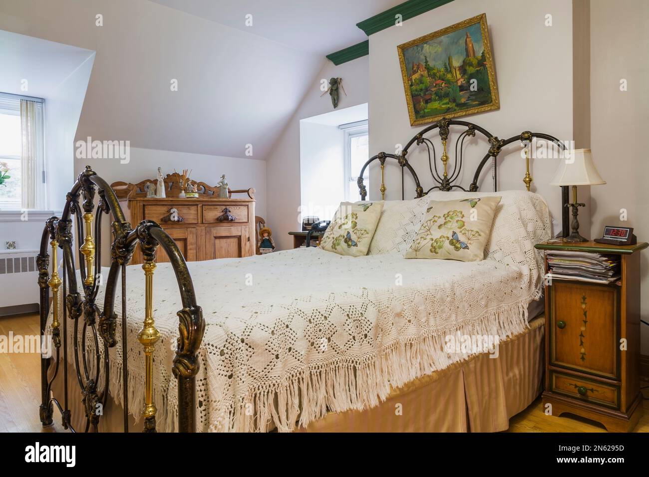 Letto matrimoniale con testiera in alluminio e ottone forgiato antico e sponda piedi nella camera da letto principale al piano superiore all'interno della vecchia casa del 1839. Foto Stock