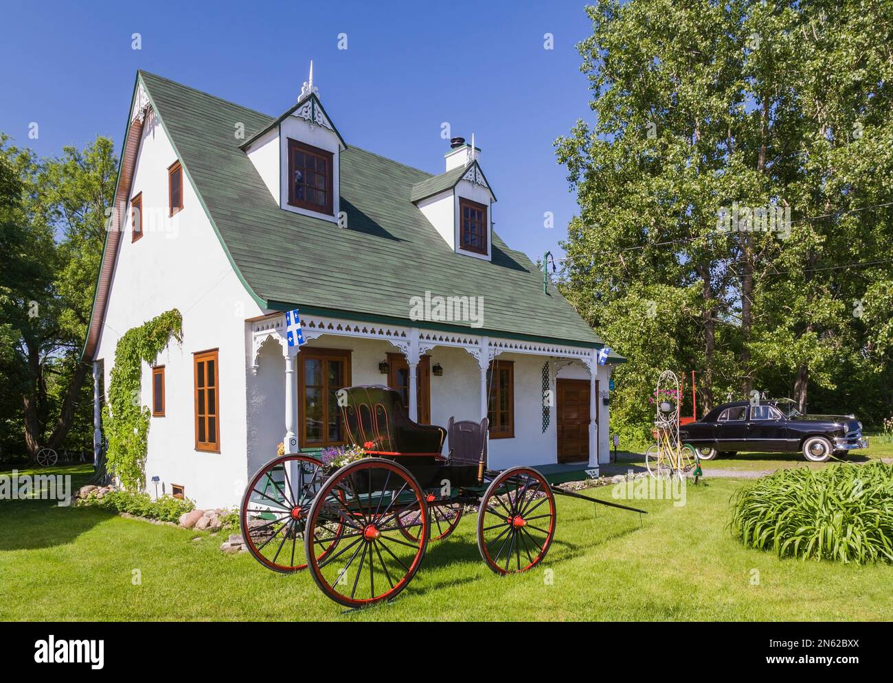 Vecchio stucco bianco 1927 con rivestimento verde stile cottage facciata casa con nero e rosso 1925 Greyson Campbell carrozza trainata da cavalli e nero 1950 Ford auto. Foto Stock