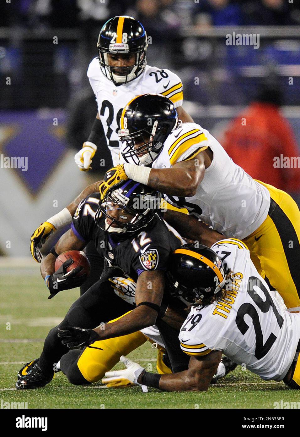 Baltimore Ravens wide receiver Jacoby Jones (12) is tackled by Pittsburgh Steelers inside linebacker Kion Wilson, center, and Pittsburgh Steelers strong safety Shamarko Thomas as Pittsburgh Steelers cornerback Cortez Allen (28) looks on in the second half of an NFL football game Thursday, Nov. 28, 2013, in Baltimore. (AP Photo/Nick Wass) Foto Stock