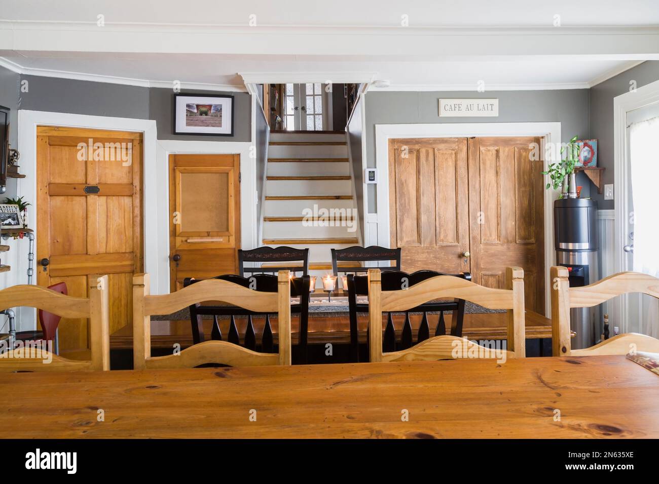 Isola con ripiano in legno di pino e sedie con schienale alto nell'area cucina più tavolo da pranzo antico con candele accese all'interno della vecchia casa del 1839. Foto Stock