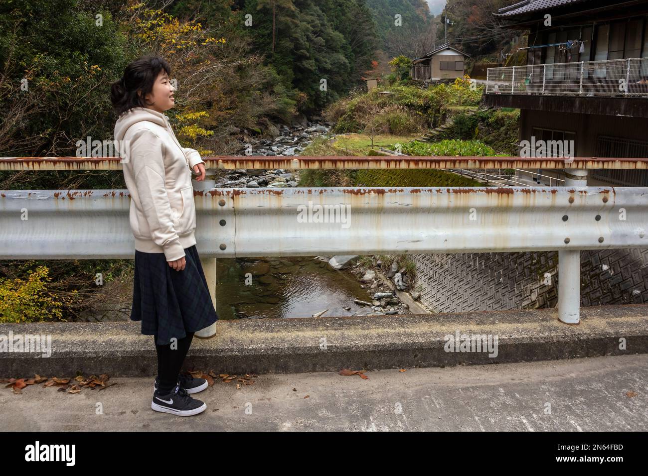 Ragazza su un ponte sul fiume Fujikamadani, montagne Shikoku, Giappone. Foto Stock