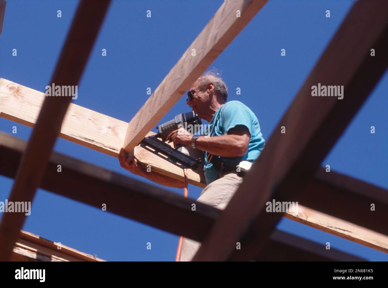 L'uomo anziano che usa un chiodatore di potere che costruisce una struttura Foto Stock