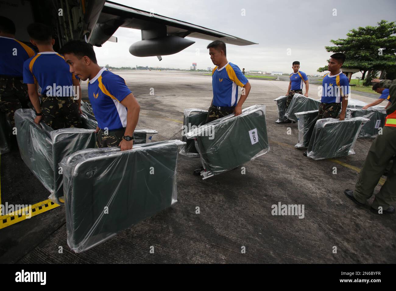 Members of the Philippine Air Force carry cots on a C130 military plane as they prepare to fly