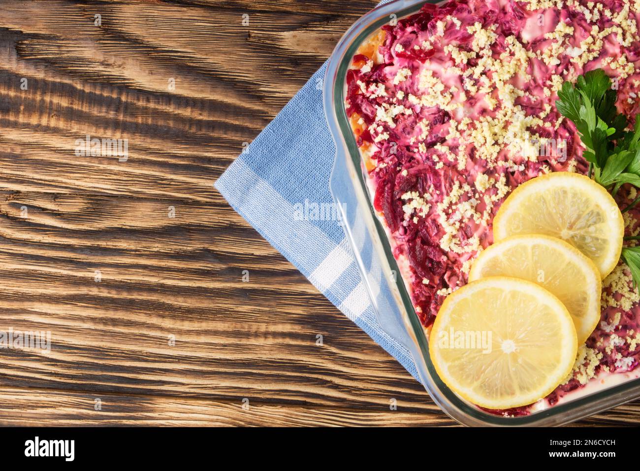 Aringa sotto pelliccia cappotto. Tradizionale insalata russa aringa sotto un cappotto di pelliccia, sfondo in legno d'annata. Insalata a strati con aringhe, barbabietole, carote, cipolla Foto Stock