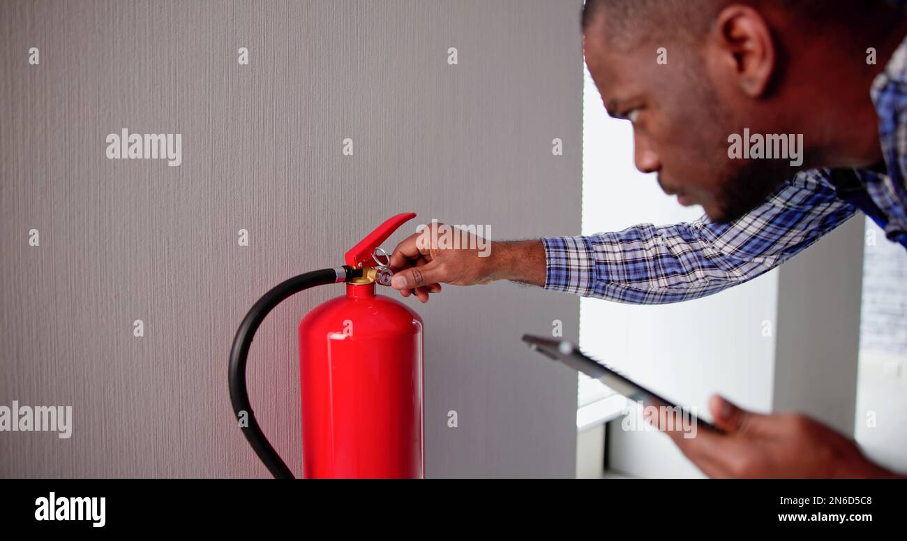 Professionista maschio che verifica Un estintore. Ispezione di sicurezza Foto Stock