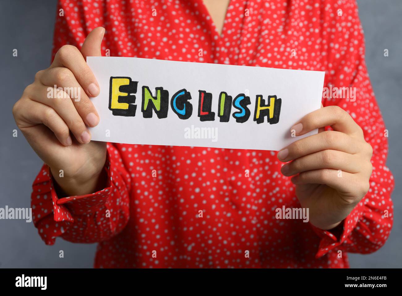 Donna che tiene foglio di carta con parola inglese su sfondo grigio, primo  piano Foto stock - Alamy