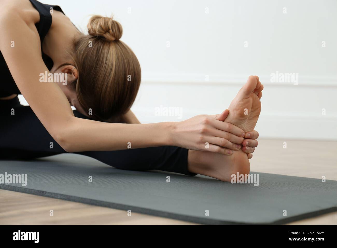 Giovane donna che pratica asana testa a ginocchio nello studio di yoga. Janu Sirsasana posa Foto Stock