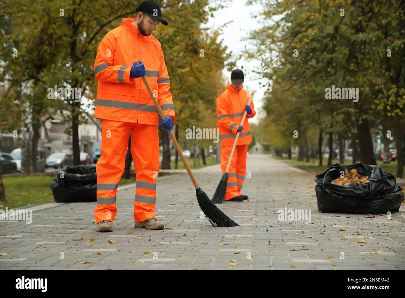 I pulitori di strada che spazzano le foglie cadute all'aperto il giorno di autunno Foto Stock